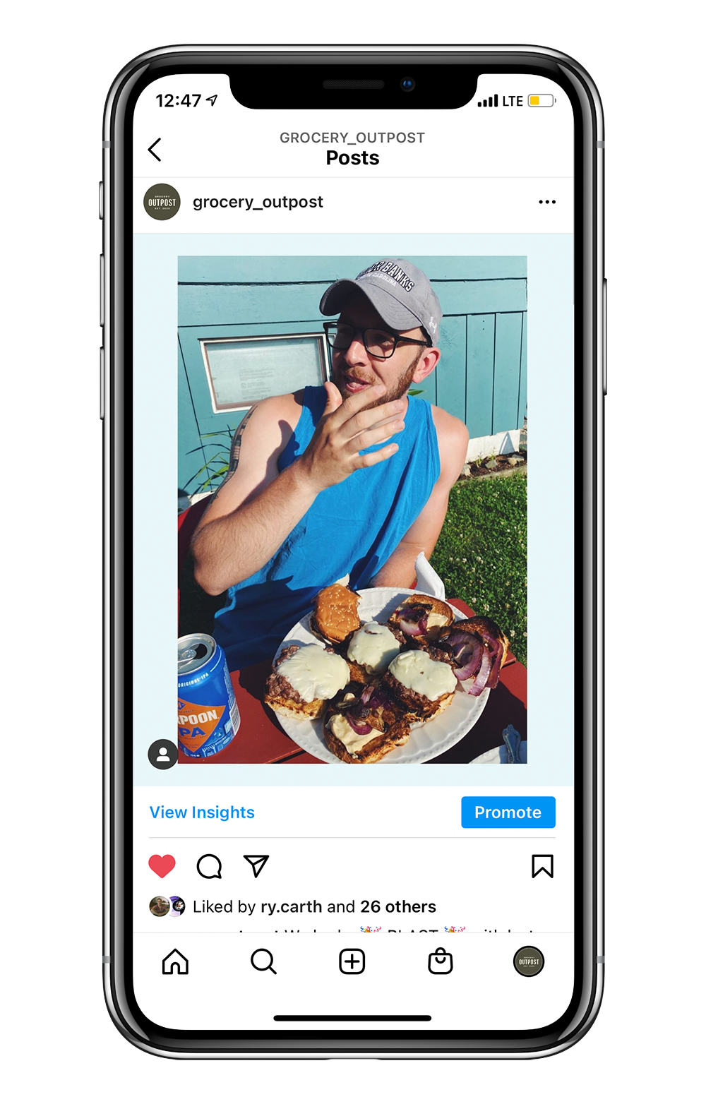 Instagram post showing a man in a blue tank top eating a hamburger.
